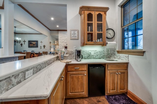 bar with refrigerator, a sink, decorative backsplash, dark wood-type flooring, and crown molding