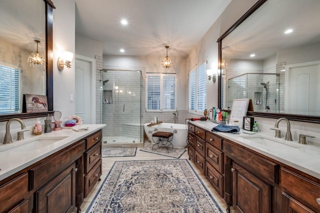 bathroom featuring a stall shower, a chandelier, and a sink