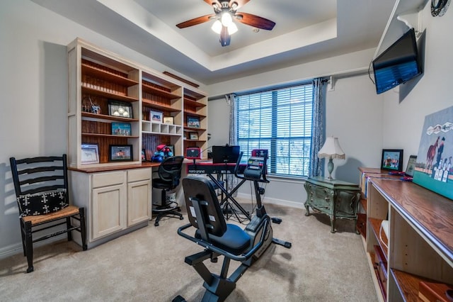 office with baseboards, ceiling fan, light carpet, built in study area, and a raised ceiling