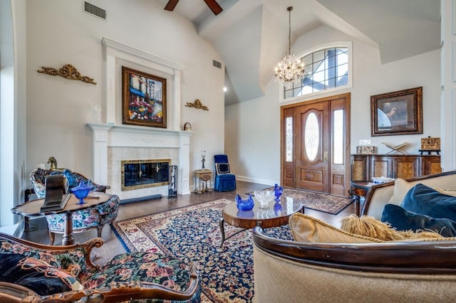 living room with wood finished floors, visible vents, high vaulted ceiling, a tile fireplace, and a notable chandelier