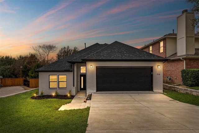 view of front of house featuring a shingled roof, a lawn, concrete driveway, an attached garage, and fence