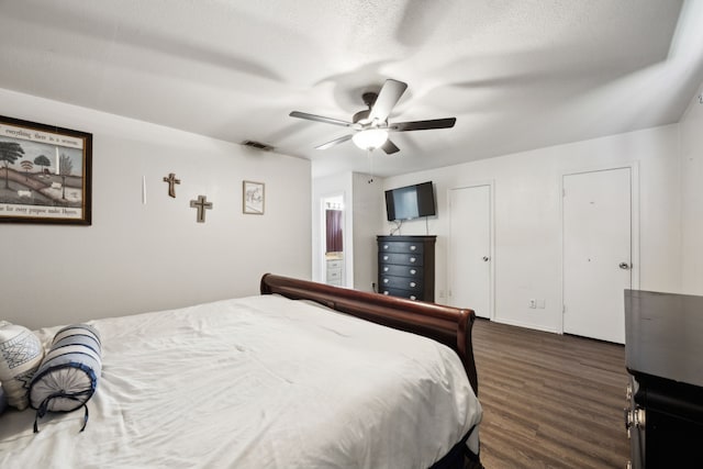 bedroom featuring visible vents, ensuite bathroom, dark wood-type flooring, ceiling fan, and a textured ceiling