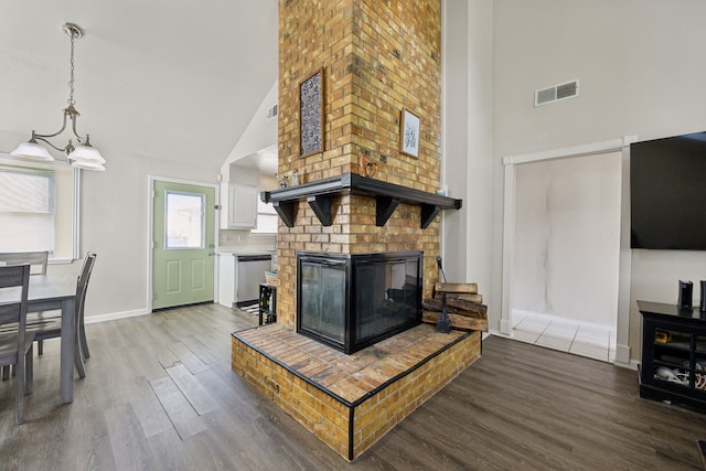 living area with high vaulted ceiling, a fireplace, wood finished floors, visible vents, and baseboards