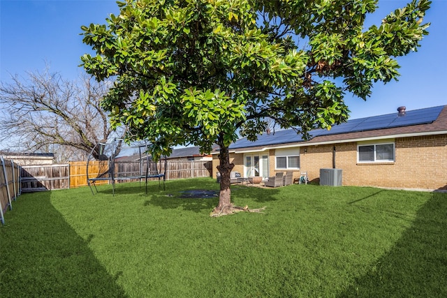 view of yard with central AC, a trampoline, and a fenced backyard