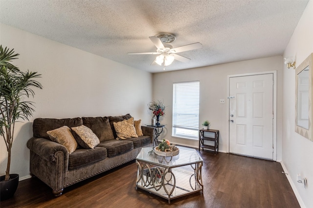 living area featuring dark wood-style floors, a textured ceiling, baseboards, and a ceiling fan