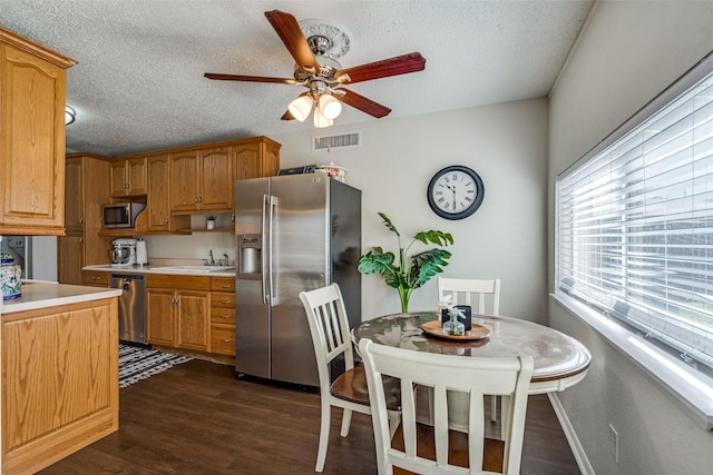 kitchen with light countertops, appliances with stainless steel finishes, dark wood-type flooring, a sink, and a textured ceiling