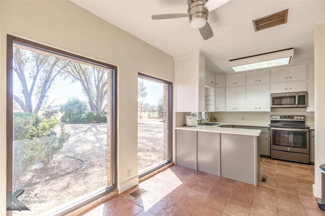 kitchen with a peninsula, a sink, visible vents, light countertops, and appliances with stainless steel finishes