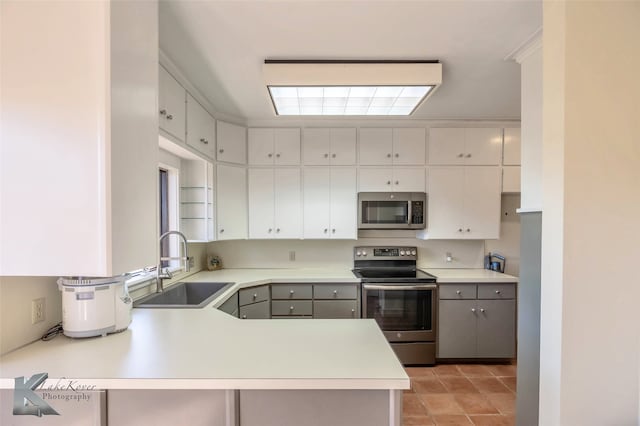 kitchen featuring stainless steel appliances, a peninsula, a sink, white cabinets, and light countertops