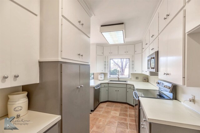 kitchen with stainless steel appliances, a sink, light countertops, and white cabinetry