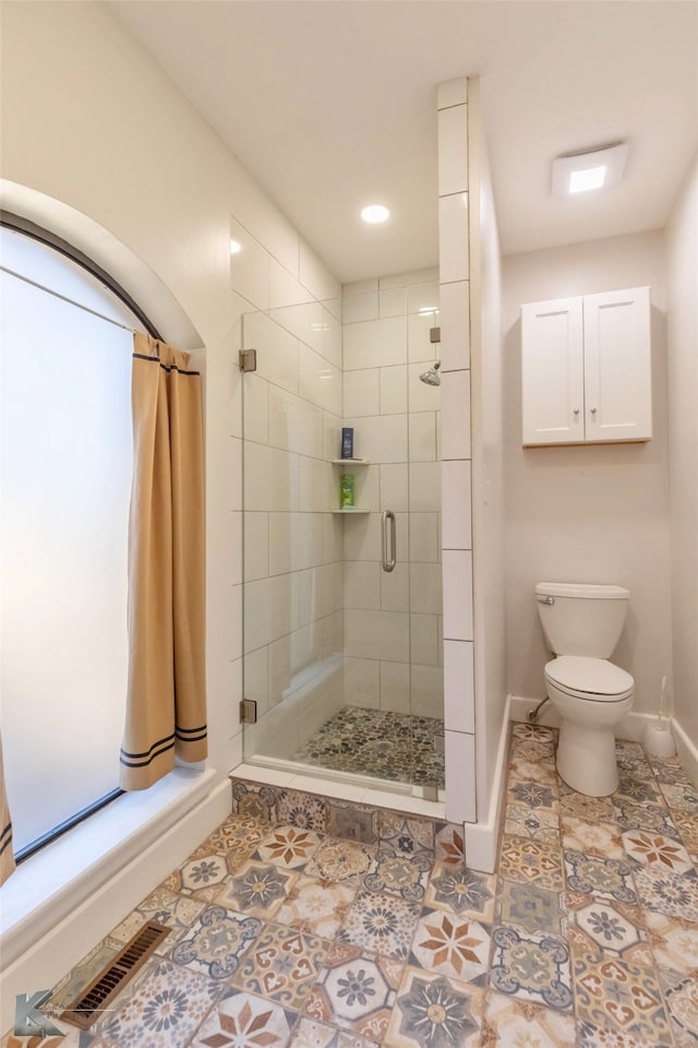 full bathroom with toilet, a stall shower, baseboards, and visible vents