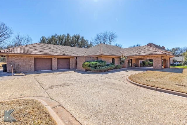 view of front facade featuring driveway, brick siding, and a tile roof