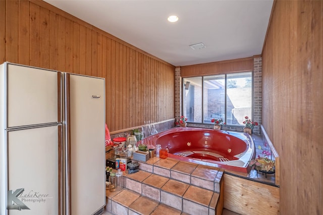 bathroom with a whirlpool tub, wooden walls, and visible vents