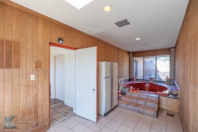 kitchen featuring freestanding refrigerator, light tile patterned flooring, and wooden walls