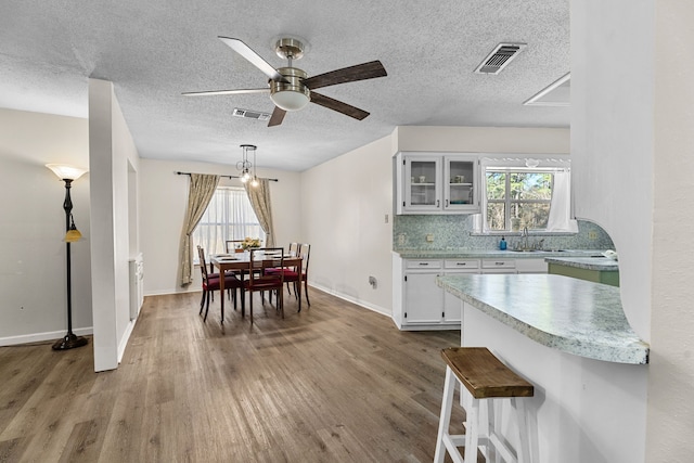 dining space with visible vents, ceiling fan, baseboards, and wood finished floors