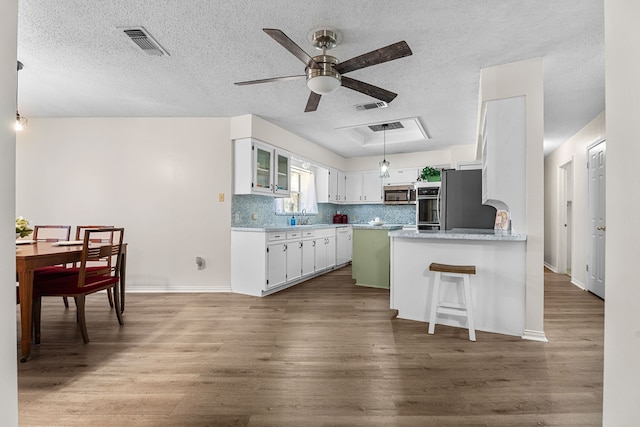 kitchen featuring refrigerator, wood finished floors, visible vents, decorative backsplash, and stainless steel microwave