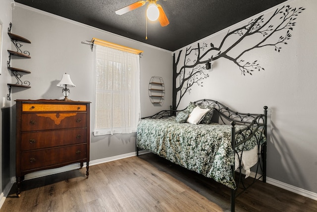 bedroom featuring a textured ceiling, wood finished floors, a ceiling fan, and baseboards