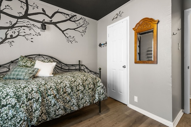 bedroom featuring crown molding, baseboards, and wood finished floors