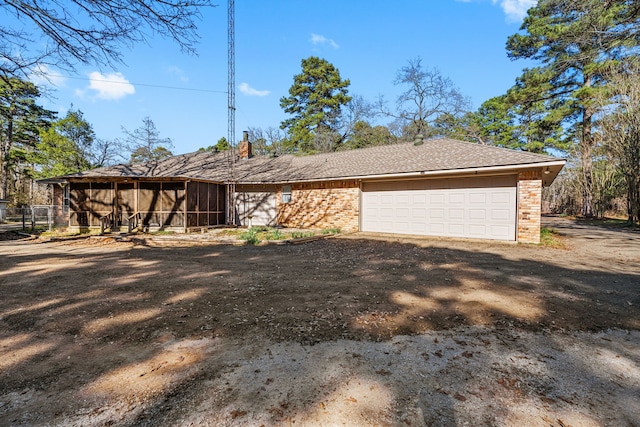 view of front of house featuring a garage, a sunroom, brick siding, and driveway