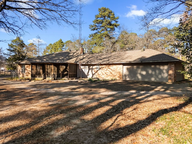 view of front of property with driveway, a sunroom, a shingled roof, and brick siding