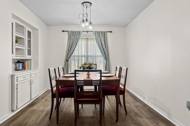 dining room with a textured ceiling, baseboards, and wood finished floors