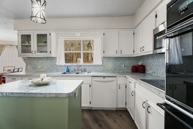 kitchen featuring a textured ceiling, a sink, light countertops, dark wood-style floors, and black appliances