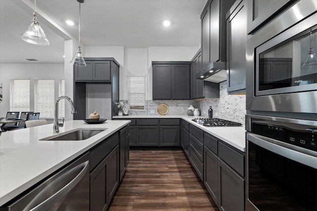 kitchen with stainless steel appliances, a sink, light countertops, range hood, and dark wood finished floors