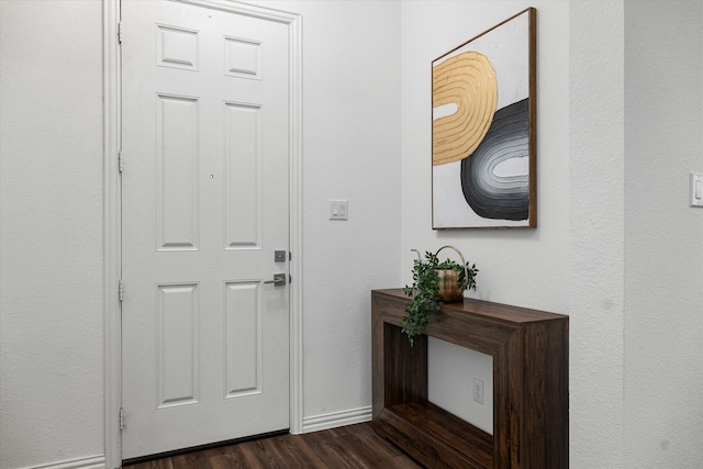 foyer featuring baseboards and dark wood-style flooring