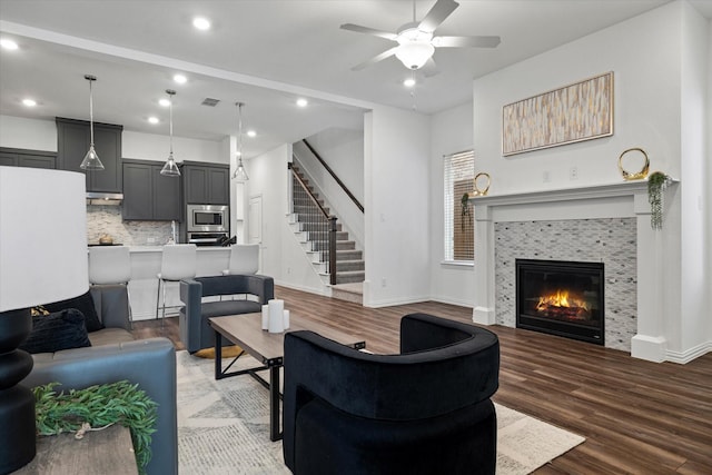 living room with visible vents, a tiled fireplace, stairway, wood finished floors, and recessed lighting