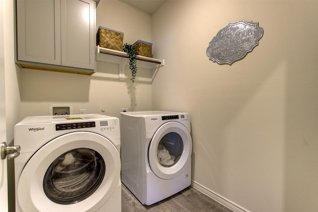 laundry area featuring wood finished floors, washing machine and clothes dryer, cabinet space, and baseboards