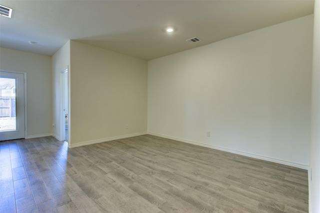 unfurnished room with light wood finished floors, visible vents, and baseboards