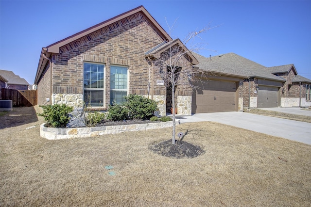 view of front of home with an attached garage, brick siding, fence, concrete driveway, and stone siding