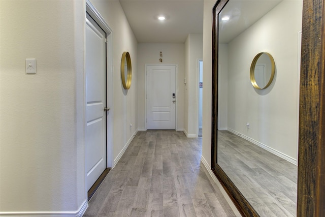 corridor with light wood finished floors, baseboards, and recessed lighting