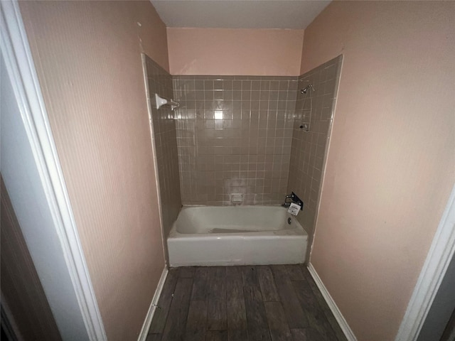 bathroom with baseboards, wood finished floors, and  shower combination