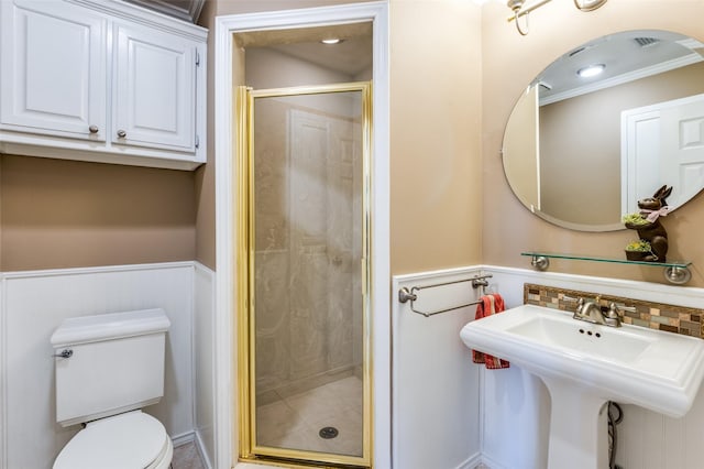 full bathroom featuring a sink, a wainscoted wall, toilet, and a shower stall