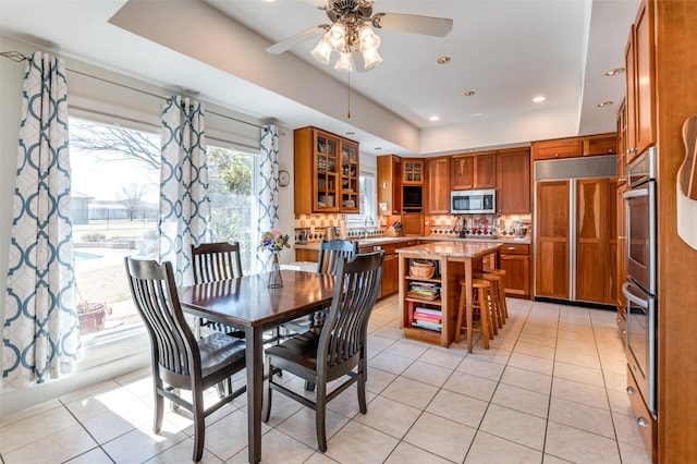 dining area with a raised ceiling, light tile patterned floors, recessed lighting, and ceiling fan