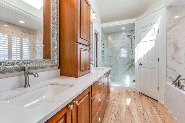 bathroom featuring a garden tub, a sink, wood finished floors, a marble finish shower, and double vanity