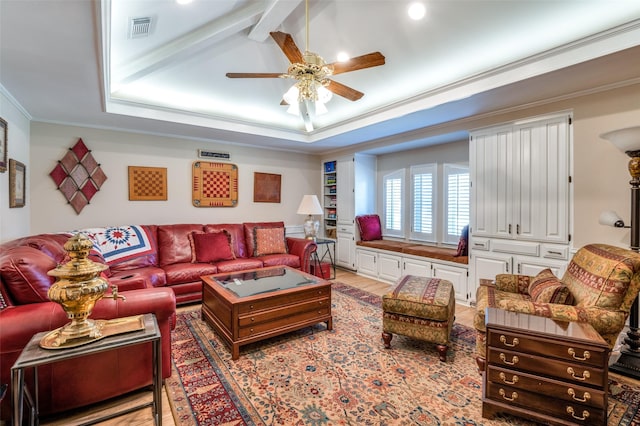 living area with light wood-type flooring, visible vents, ornamental molding, a ceiling fan, and a raised ceiling