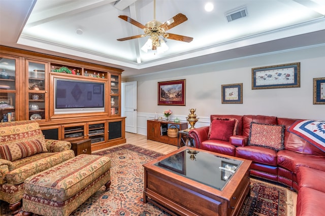 living room featuring visible vents, crown molding, a tray ceiling, wood finished floors, and a ceiling fan