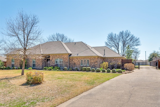 view of front of home featuring a front lawn, brick siding, and a shingled roof