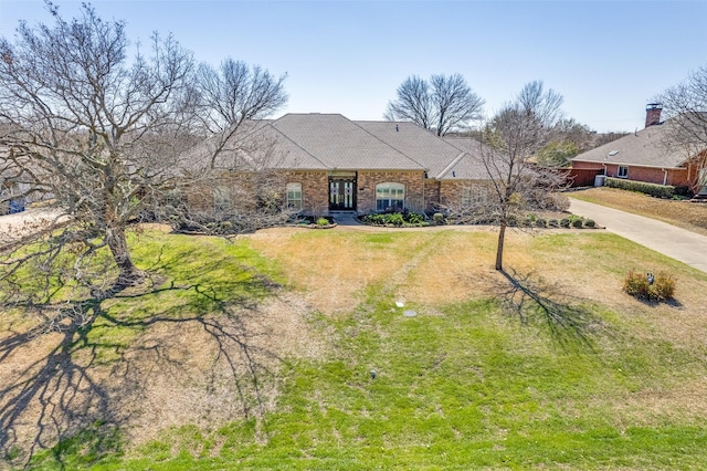 view of front facade featuring a front lawn, concrete driveway, and brick siding