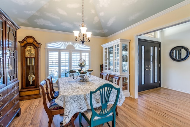 dining room with ornamental molding, baseboards, light wood-type flooring, and a chandelier