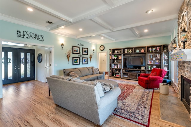 living area with visible vents, beam ceiling, a stone fireplace, recessed lighting, and wood finished floors