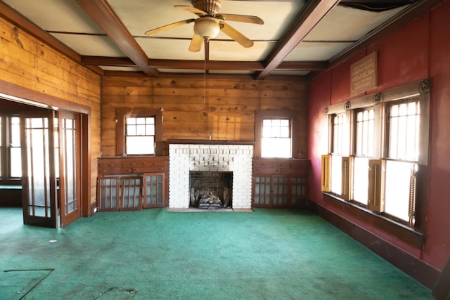 unfurnished living room with a healthy amount of sunlight, beamed ceiling, and wooden walls