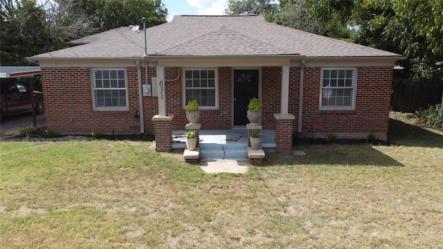 view of front of house featuring a shingled roof, a front yard, and brick siding