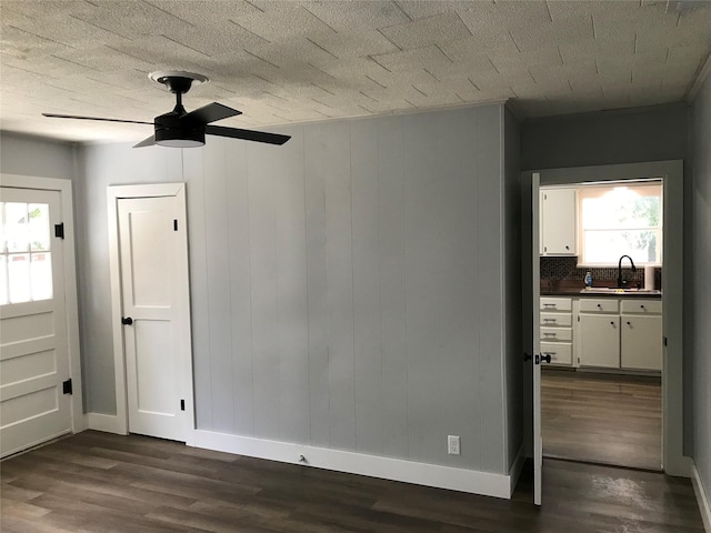 unfurnished room with ceiling fan, baseboards, dark wood finished floors, and a sink