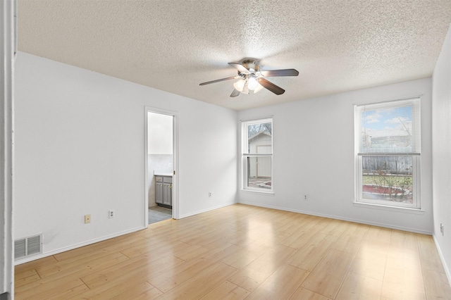 spare room featuring baseboards, visible vents, ceiling fan, and light wood finished floors