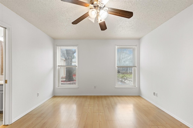 spare room with light wood-type flooring, plenty of natural light, and baseboards