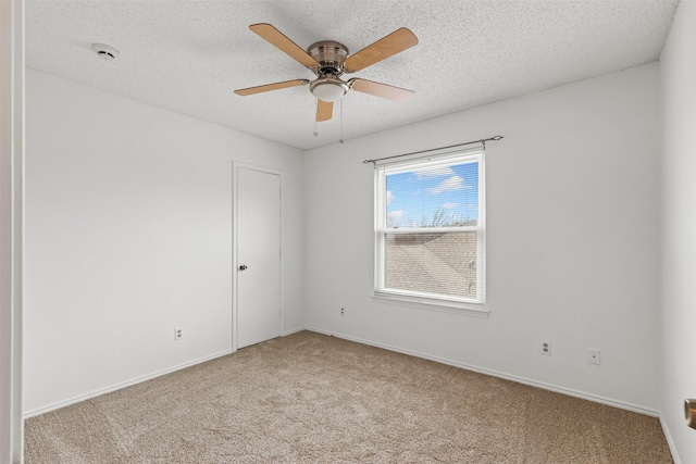 empty room featuring a ceiling fan, carpet flooring, a textured ceiling, and baseboards