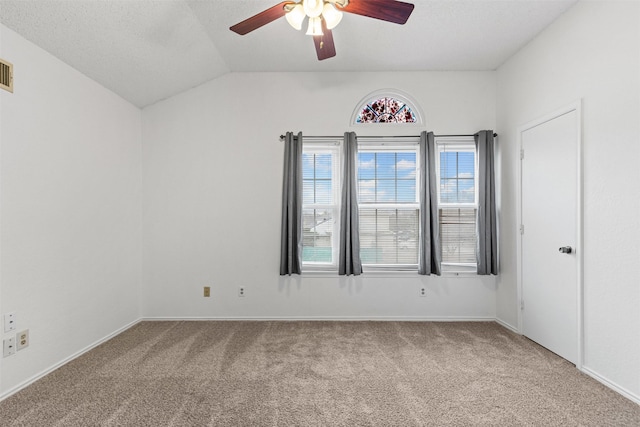 carpeted spare room with vaulted ceiling, a textured ceiling, and a ceiling fan