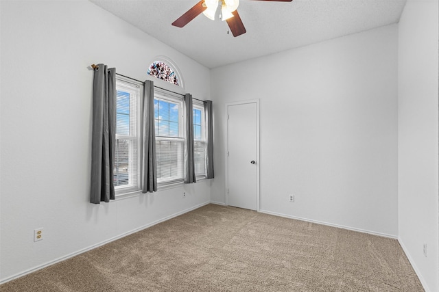 carpeted empty room featuring a ceiling fan, a textured ceiling, and baseboards